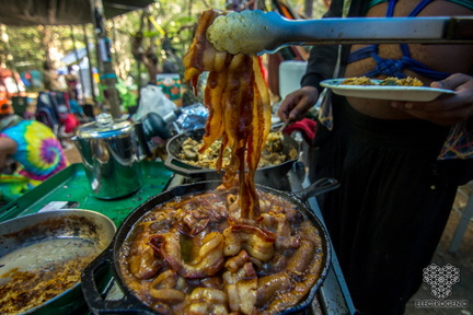 KyleR.2012 Bacon and sausage sizzling in a pan inside a makeshift kitchen.